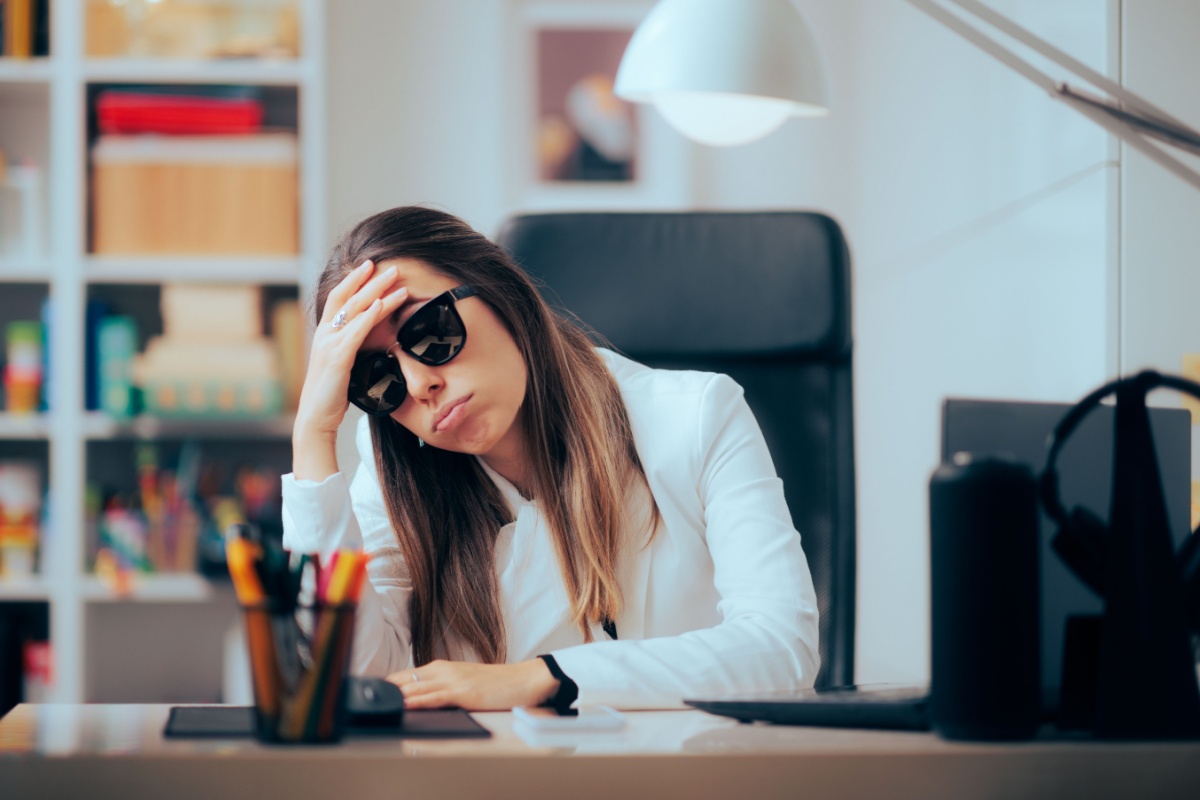 Woman wearing her sunglasses inside while working due to light sensitivity from dry eye syndrome.